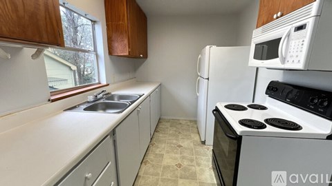 A kitchen with white appliances and brown cabinets.