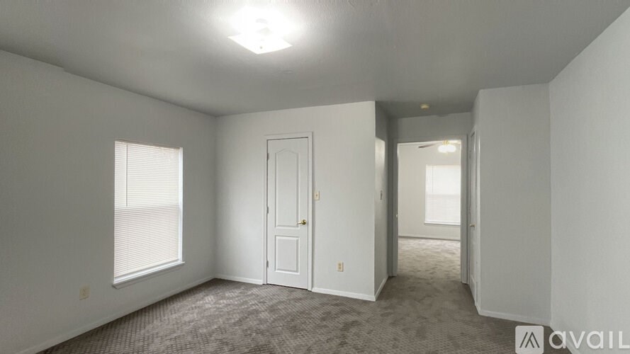 A room with a carpeted floor, a window with blinds, and a door.