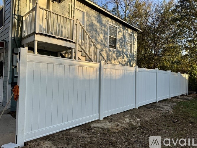 A white fence is in front of a house.