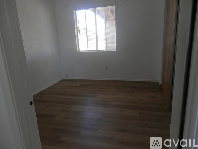 A room with wooden flooring and a window letting in sunlight.