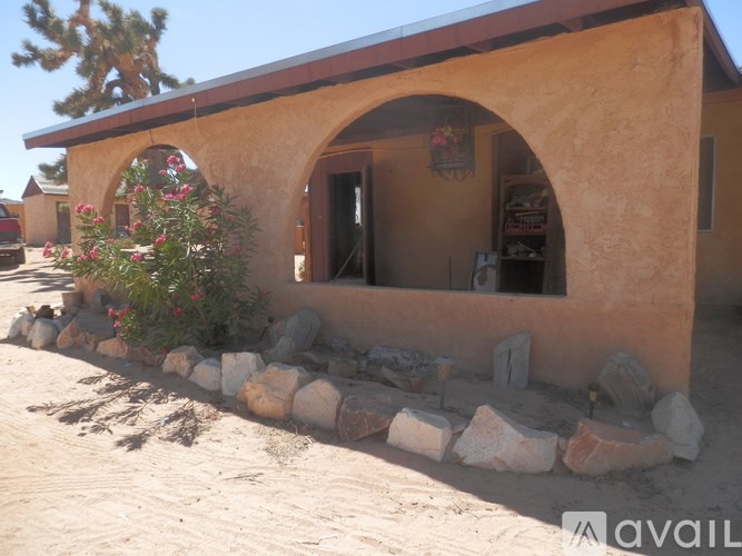 A small house with a brown roof and a stone wall in front.