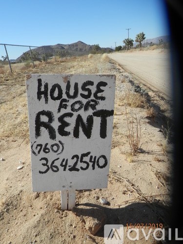 A sign in the desert advertises a house for rent.