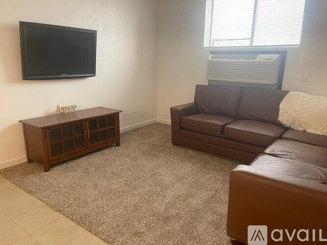 A living room with a brown couch, a wooden coffee table, and a flat screen TV mounted on the wall.