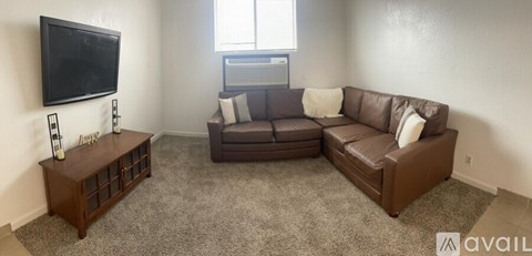 A living room with a brown couch and a television mounted on the wall.