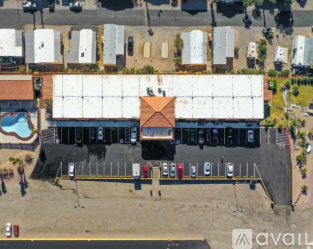 A parking lot with a building and a pool in the background.