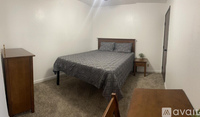A bedroom with a bed, nightstand, and a wooden cabinet.