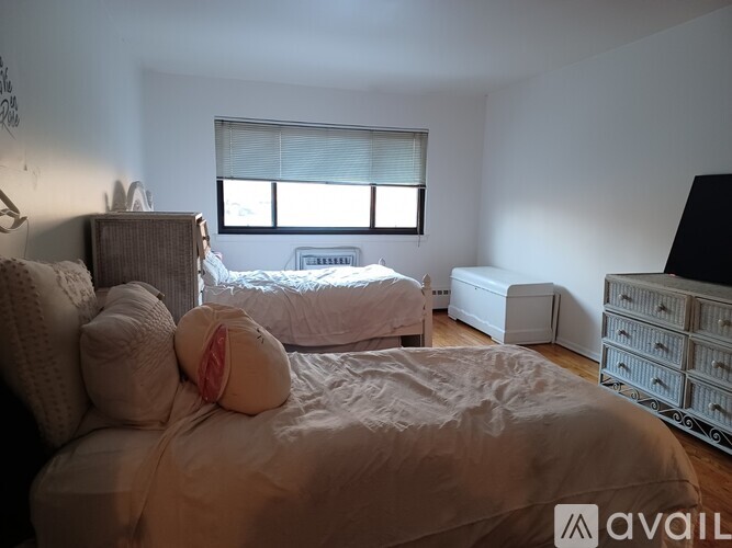 A bedroom with a large bed and a window with blinds.