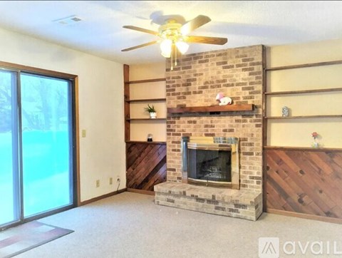 A living room with a fireplace and a ceiling fan.