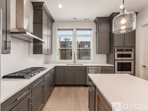 A modern kitchen with dark grey cabinets and stainless steel appliances.