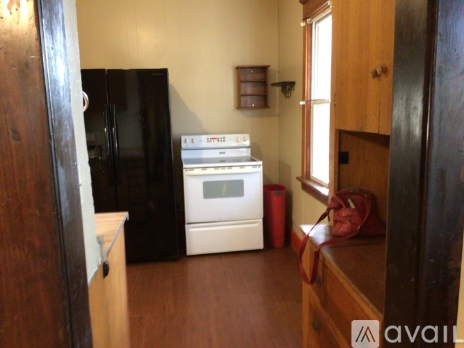 A kitchen with a black fridge, white oven and wooden cabinets.