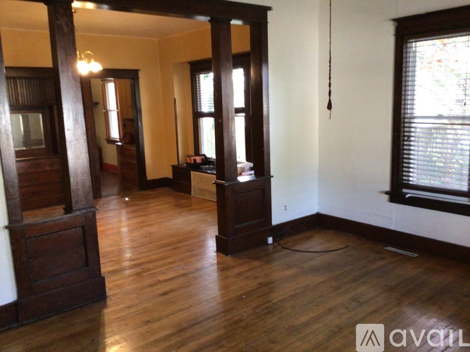 A room with wooden floors and a large window with blinds.