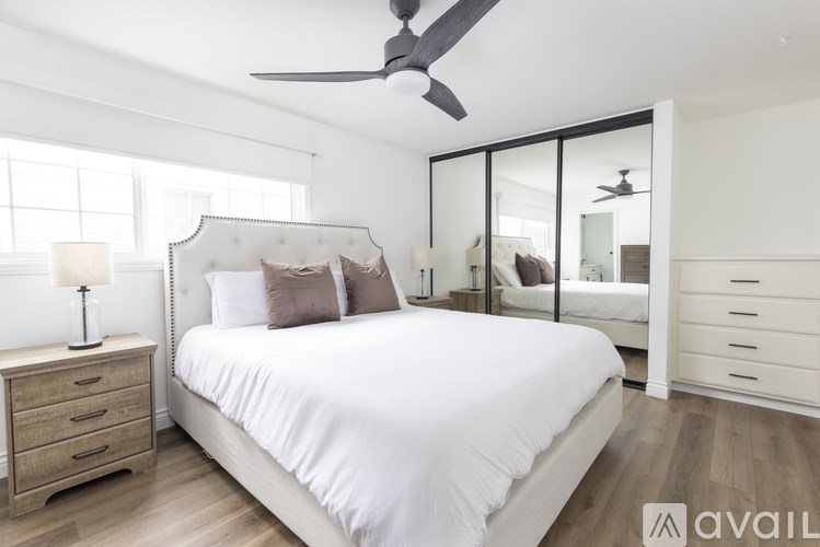 A bedroom with a large bed, a dresser, and a ceiling fan.