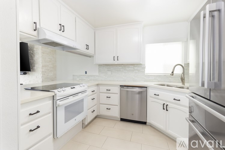 A kitchen with white cabinets and appliances.