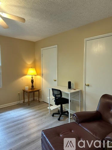 A bedroom with a bed, chair, and lamp.