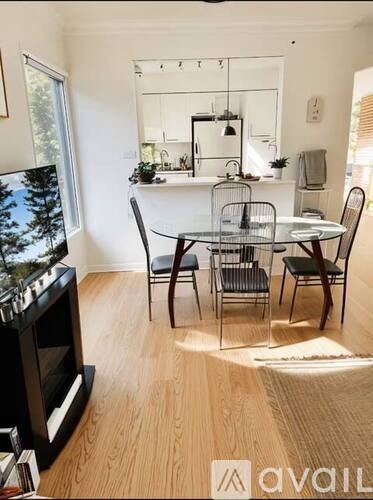 A modern living room with a television, a dining table, and chairs.