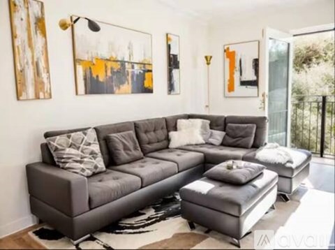 A grey sectional sofa with pillows and ottoman in a living room.