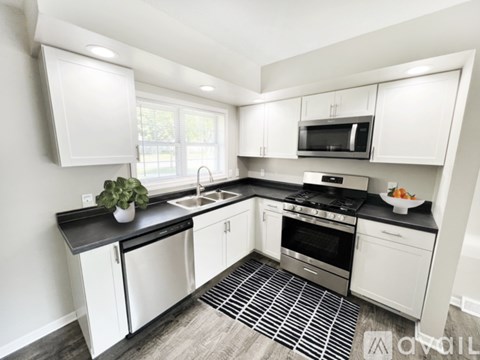A modern kitchen with white cabinets and black countertops.
