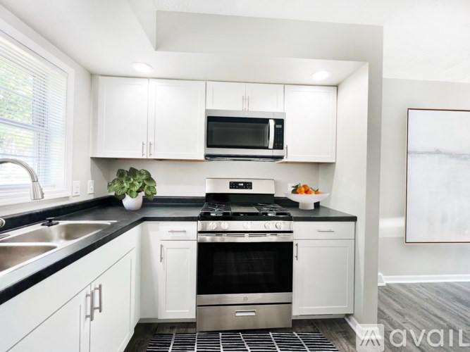 A modern kitchen with white cabinets and black countertops.