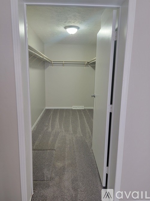 A small, empty room with a carpeted floor and a single light fixture on the ceiling.