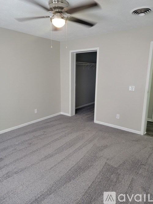 A room with a ceiling fan and carpeted floor.