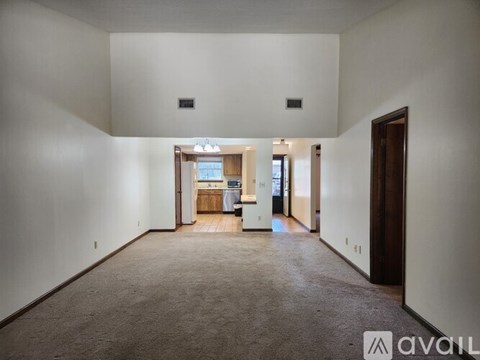 A spacious living room with a kitchen in the background.