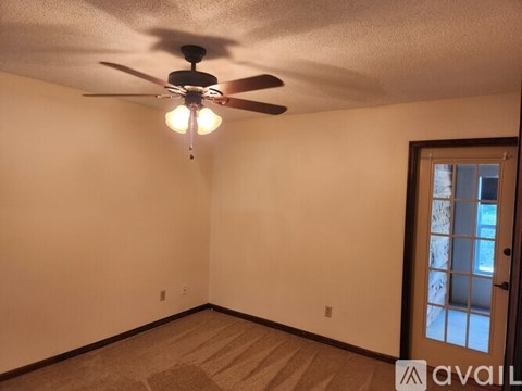 A room with a ceiling fan and a door.