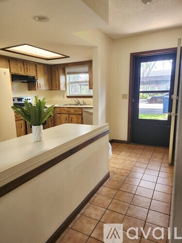 A residential street lined with houses and trees under a clear blue sky.