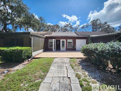 A house with a brown door and a grey walkway in front.