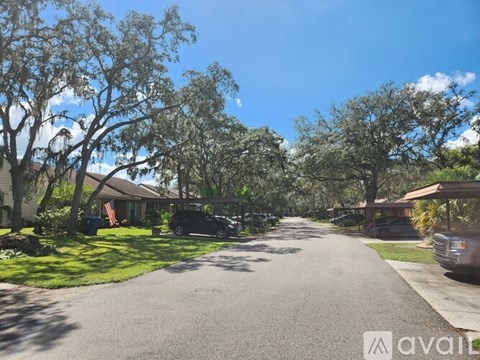 A residential street with houses on both sides and cars parked on the side.