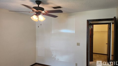 A room with a ceiling fan and a door.