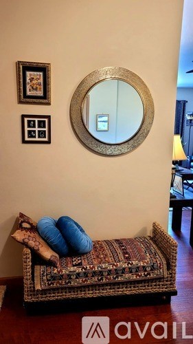 A round mirror hangs on a wall above a patterned couch.