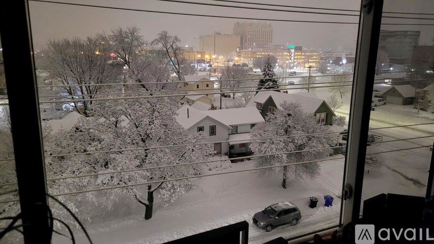 A person is standing in the snow outside a building.