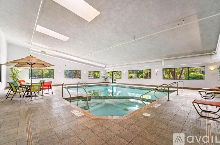 A large indoor swimming pool with a glass enclosure and a sun lounger.