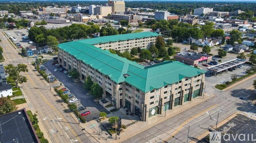 An aerial view of a large building with a green roof in the middle of a parking lot.