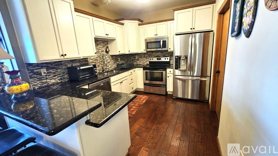 A kitchen with white cabinets and a black countertop.