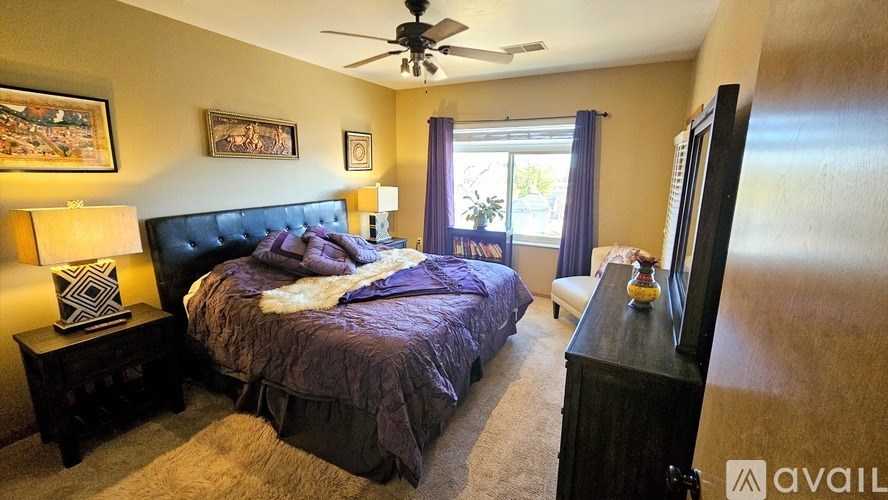 A bedroom with a large bed and a ceiling fan.