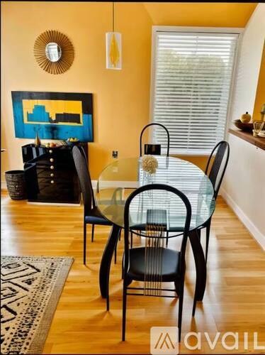A glass dining table with four chairs in the foreground.