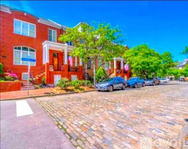 A red brick house with a blue car parked in front.