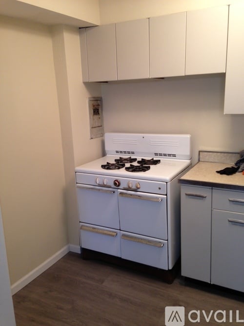 A white stove in a kitchen with white cabinets.