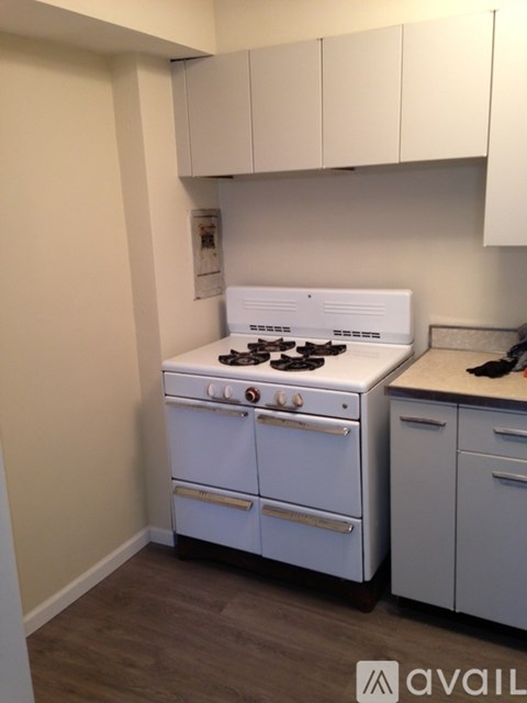 A white stove in a kitchen with white cabinets.