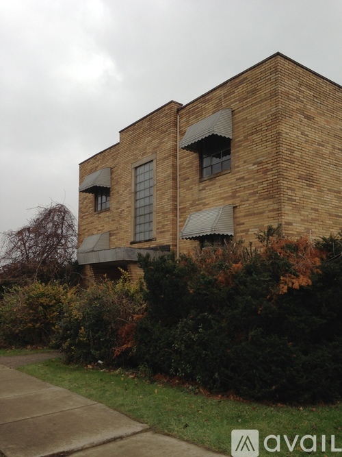 A brick building with a window and a bush in front.
