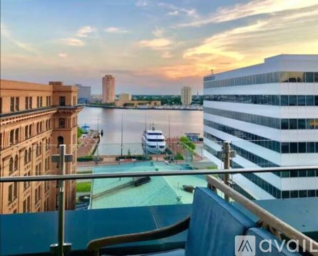 A balcony overlooks a river with boats and buildings in the distance during sunset.