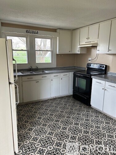 A kitchen with a black stove top oven and a black and white floor.