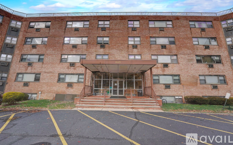 A large brick building with a glass entrance and a parking lot in front.