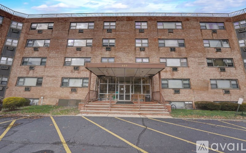 A large brick building with a glass entrance and a parking lot in front.