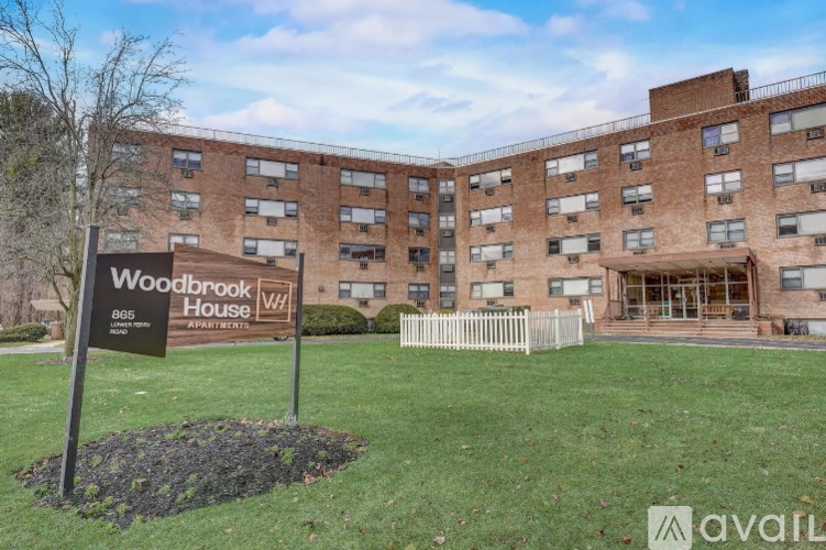 A sign for Woodbrook House stands in front of a brick building.
