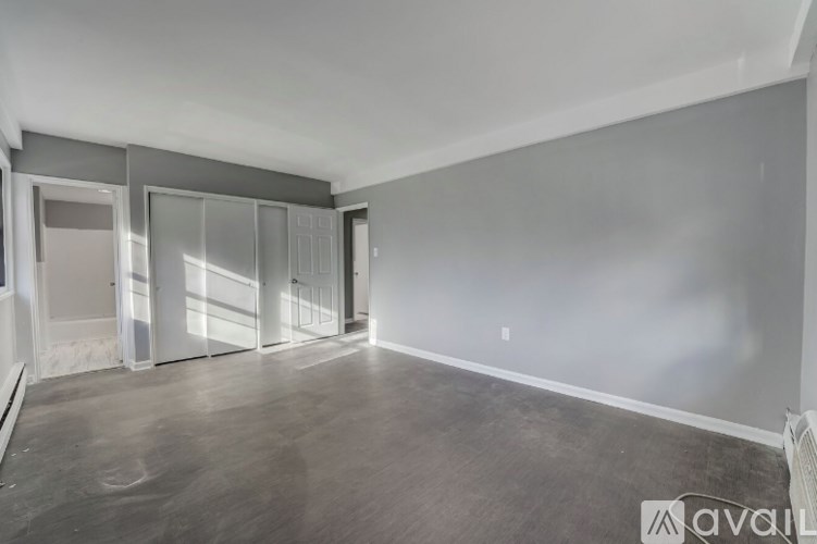 A spacious room with a grey floor and white walls, featuring a row of glass doors.