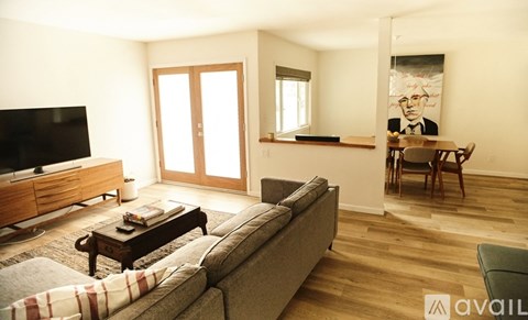 A living room with a grey couch, a wooden coffee table, a television, and a painting on the wall.