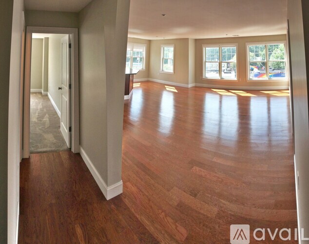 A spacious room with wooden floors and large windows.