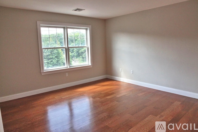 A room with wooden floors and a window letting in light.